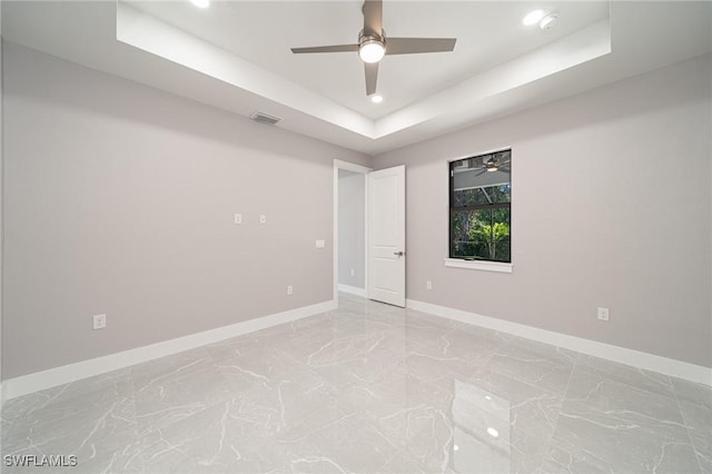 spare room with ceiling fan and a tray ceiling