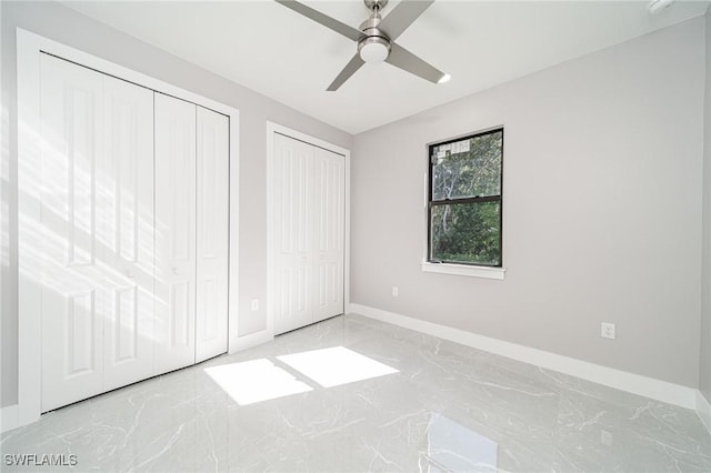 unfurnished bedroom with ceiling fan and two closets