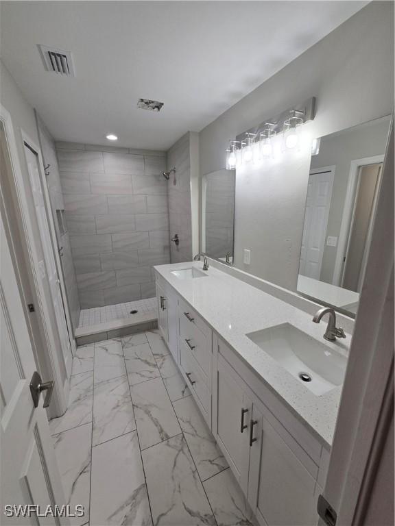 bathroom featuring tiled shower and vanity