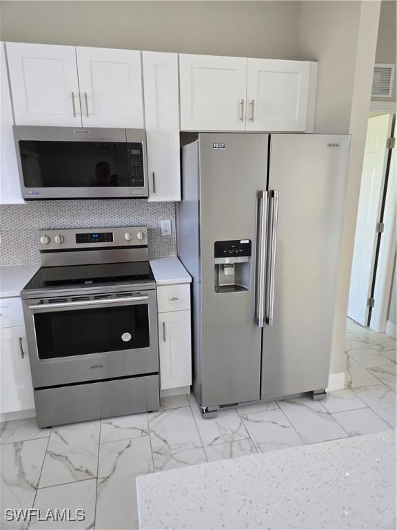 kitchen featuring stainless steel appliances, decorative backsplash, and white cabinetry