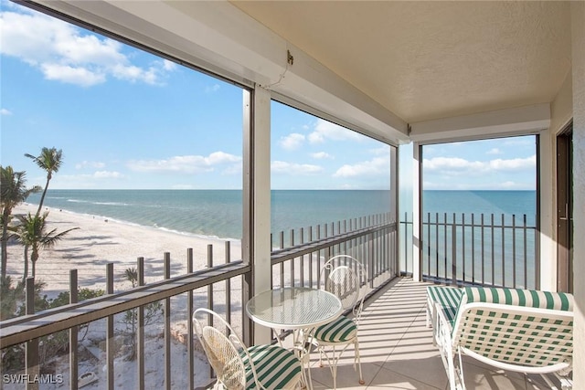 sunroom with a water view and a beach view