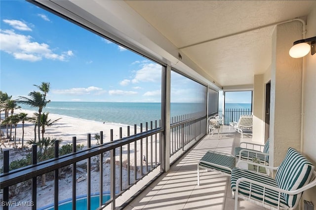 balcony featuring a water view and a beach view