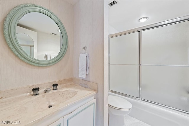 full bathroom with toilet, bath / shower combo with glass door, and vanity