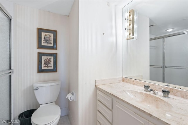 bathroom with toilet, a shower with shower door, and vanity