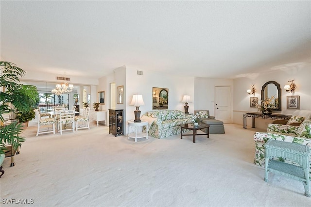 carpeted living room with an inviting chandelier