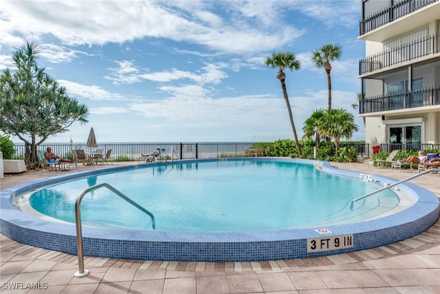 view of pool with a water view and a patio area