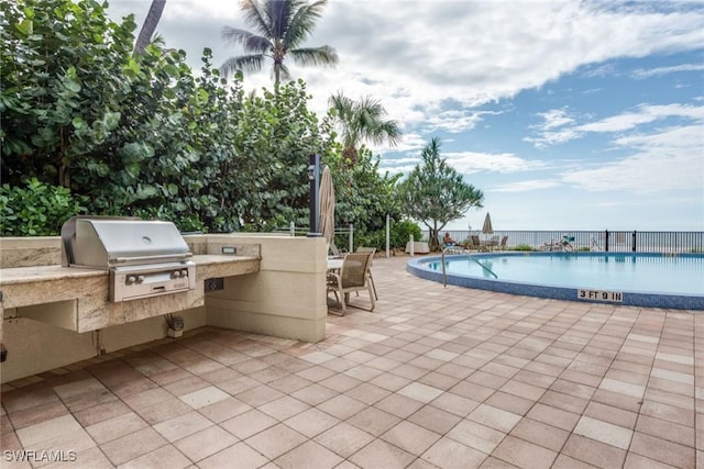 view of patio / terrace featuring a community pool, an outdoor kitchen, and area for grilling