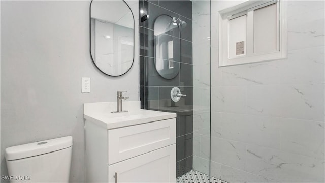 bathroom with toilet, vanity, and a tile shower