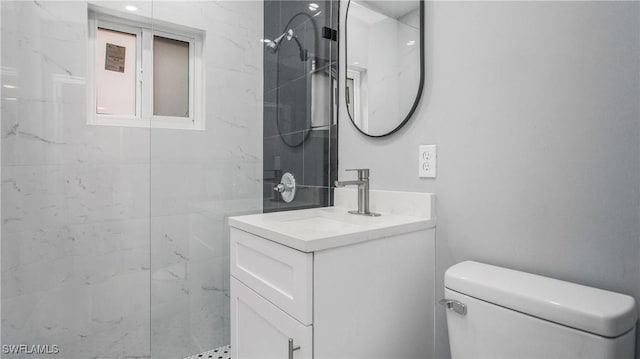 bathroom with toilet, vanity, and tiled shower