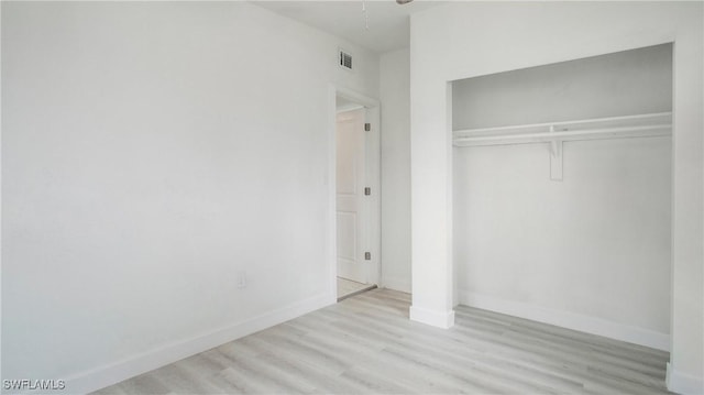 unfurnished bedroom with light wood-type flooring and a closet