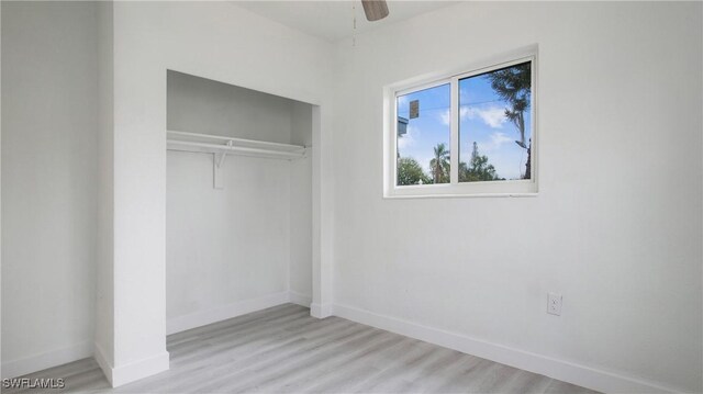 unfurnished bedroom with ceiling fan, a closet, and light wood-type flooring