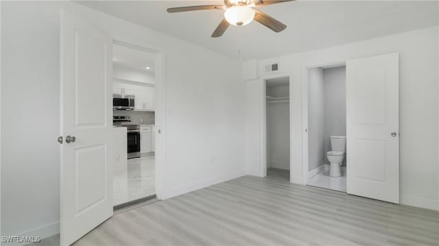 unfurnished bedroom with ensuite bathroom, ceiling fan, light wood-type flooring, and a closet