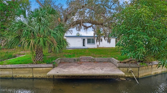 rear view of property featuring a water view and a lawn