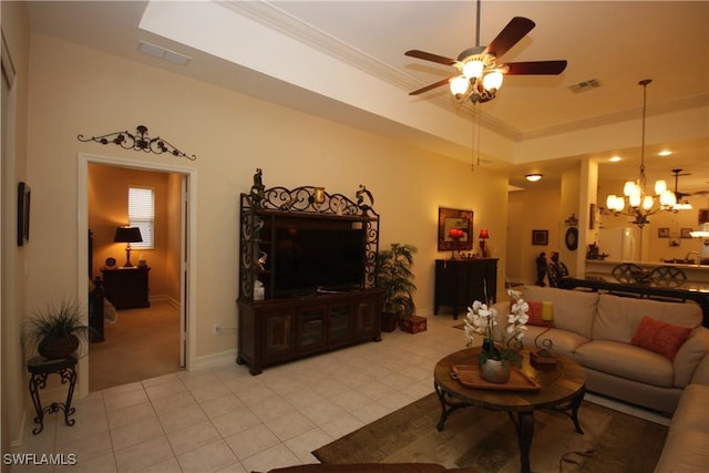 living room featuring ornamental molding, a tray ceiling, ceiling fan with notable chandelier, and light tile patterned floors