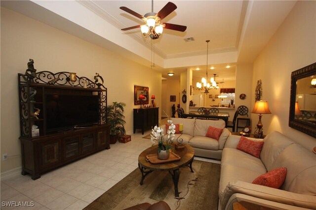 tiled living room featuring a raised ceiling and ceiling fan with notable chandelier