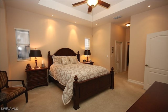 bedroom featuring a tray ceiling, light colored carpet, and ceiling fan