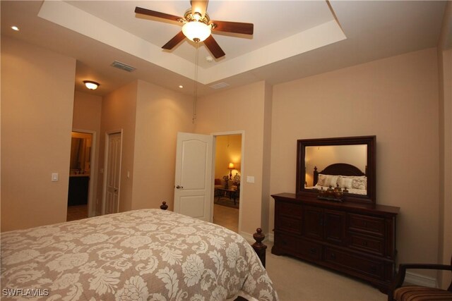 carpeted bedroom with a tray ceiling and ceiling fan