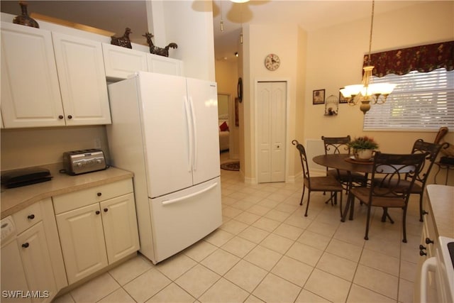 kitchen featuring light tile patterned floors, white cabinets, decorative light fixtures, a chandelier, and white fridge