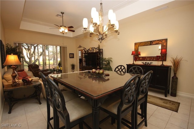 tiled dining room with a tray ceiling, ornamental molding, and ceiling fan