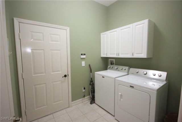 laundry area with independent washer and dryer, cabinets, and light tile patterned floors