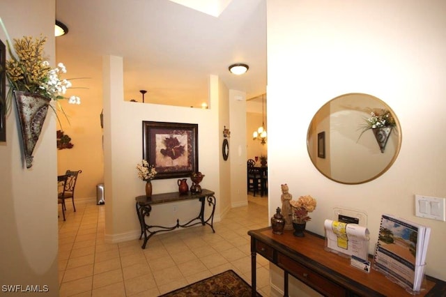 hall featuring light tile patterned flooring and a chandelier