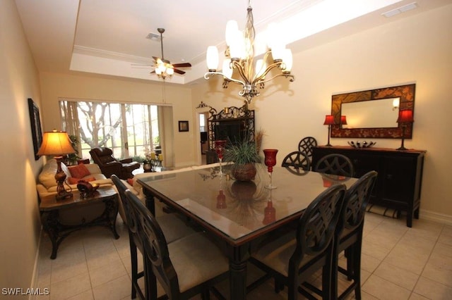 dining area with a raised ceiling, crown molding, ceiling fan with notable chandelier, and light tile patterned floors