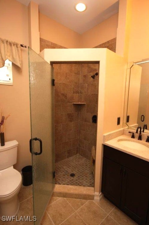 bathroom featuring vanity, an enclosed shower, tile patterned floors, and toilet