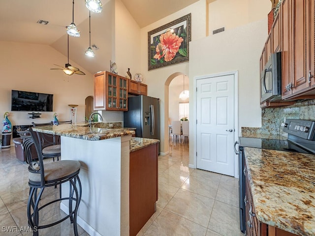 kitchen featuring pendant lighting, ceiling fan, black range with electric stovetop, light stone counters, and a kitchen bar