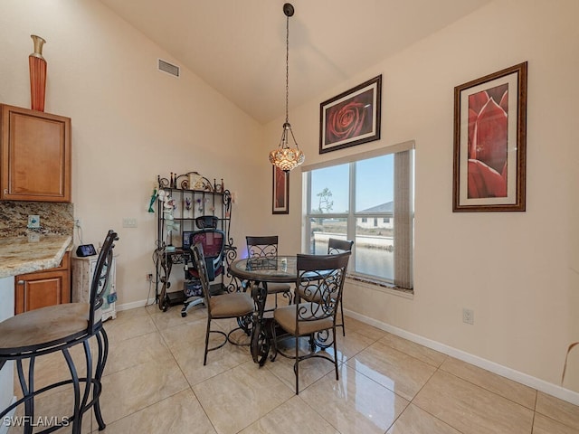 dining room featuring light tile patterned flooring, vaulted ceiling, and a notable chandelier