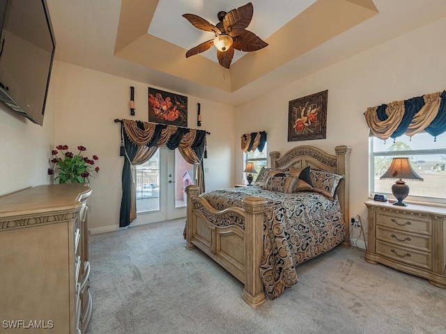 carpeted bedroom featuring ceiling fan, a tray ceiling, and access to exterior