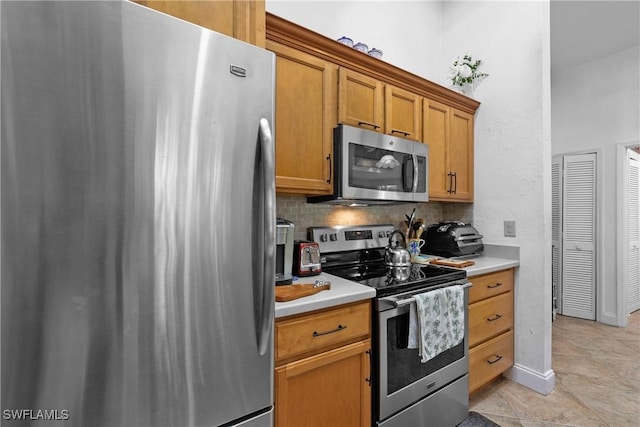 kitchen with light tile patterned flooring, decorative backsplash, and appliances with stainless steel finishes