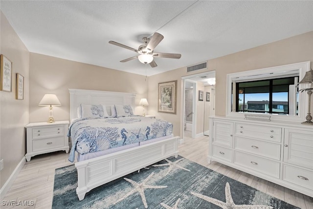 bedroom with ceiling fan, connected bathroom, light hardwood / wood-style flooring, and a textured ceiling