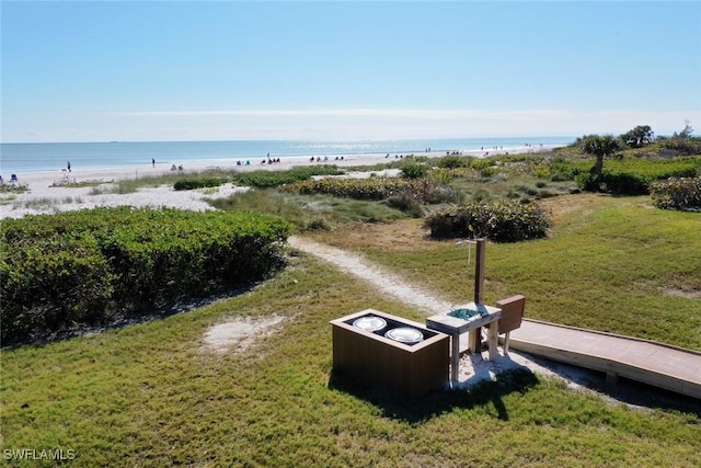 exterior space featuring a beach view, a lawn, and a water view