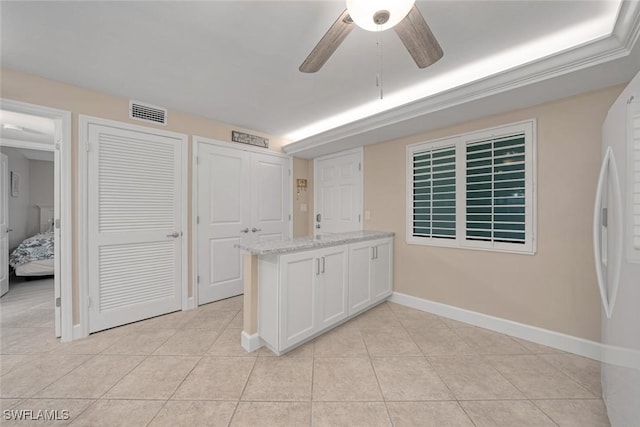 interior space featuring light stone countertops, light tile patterned floors, white cabinets, ceiling fan, and white refrigerator