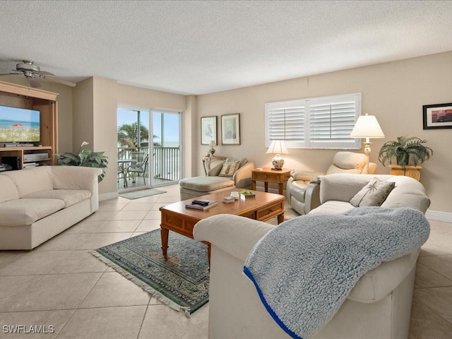 living room with a textured ceiling, ceiling fan, and light tile patterned floors