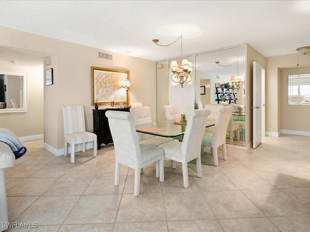 dining space featuring a textured ceiling, a chandelier, and light tile patterned floors