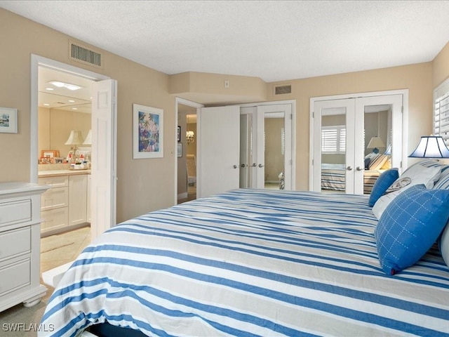 bedroom featuring ensuite bath, a textured ceiling, and two closets