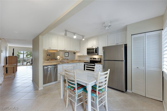 kitchen with light tile patterned floors, appliances with stainless steel finishes, white cabinetry, and sink