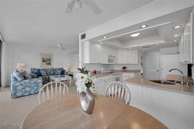 tiled dining area featuring sink, a raised ceiling, ceiling fan, and crown molding