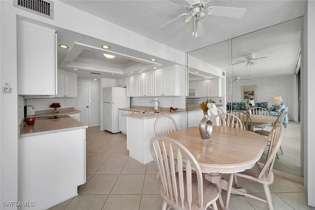 dining room with sink, light tile patterned flooring, ceiling fan, and a tray ceiling