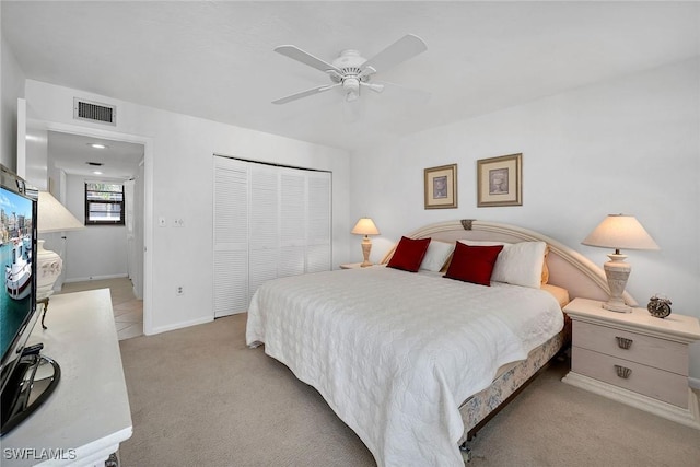 bedroom with ceiling fan, light colored carpet, and a closet