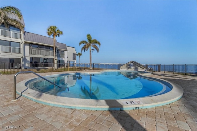 view of swimming pool with a patio and a water view