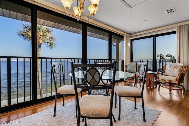 sunroom featuring a notable chandelier and a water view