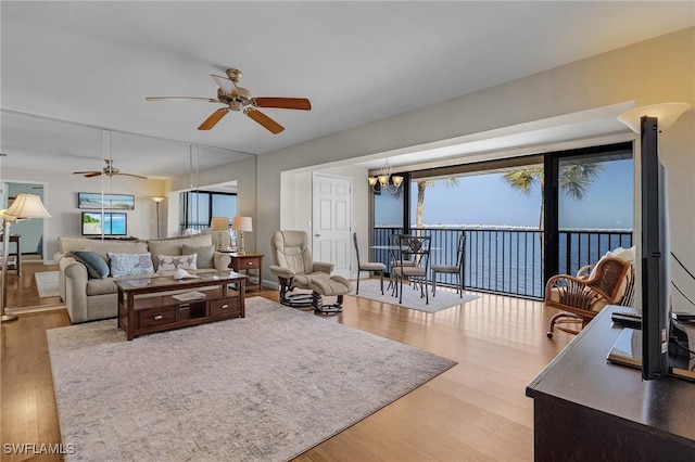 living room with ceiling fan with notable chandelier and hardwood / wood-style flooring