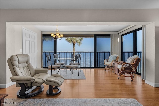 living area with plenty of natural light, hardwood / wood-style flooring, a chandelier, and a water view