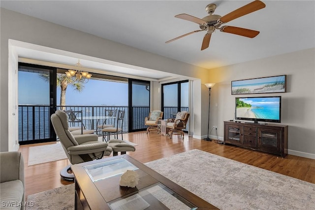 living room featuring ceiling fan with notable chandelier and hardwood / wood-style floors