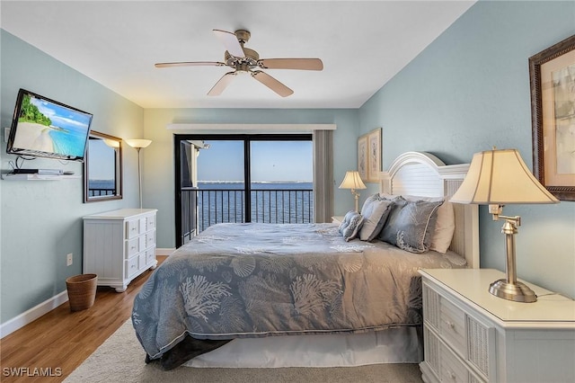 bedroom featuring light wood-type flooring, ceiling fan, access to exterior, and a water view