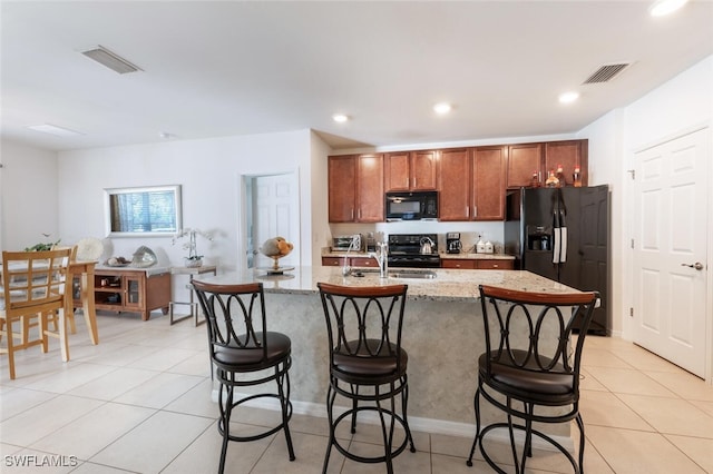 kitchen featuring black appliances, sink, a center island with sink, and light tile patterned floors