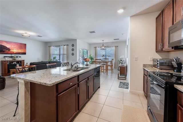 kitchen with a kitchen island with sink, black appliances, light stone countertops, light tile patterned floors, and sink