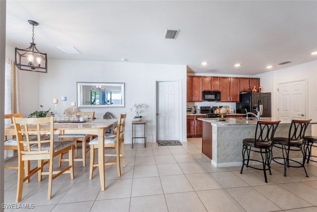 kitchen with black appliances, light tile patterned floors, a notable chandelier, light stone counters, and decorative light fixtures